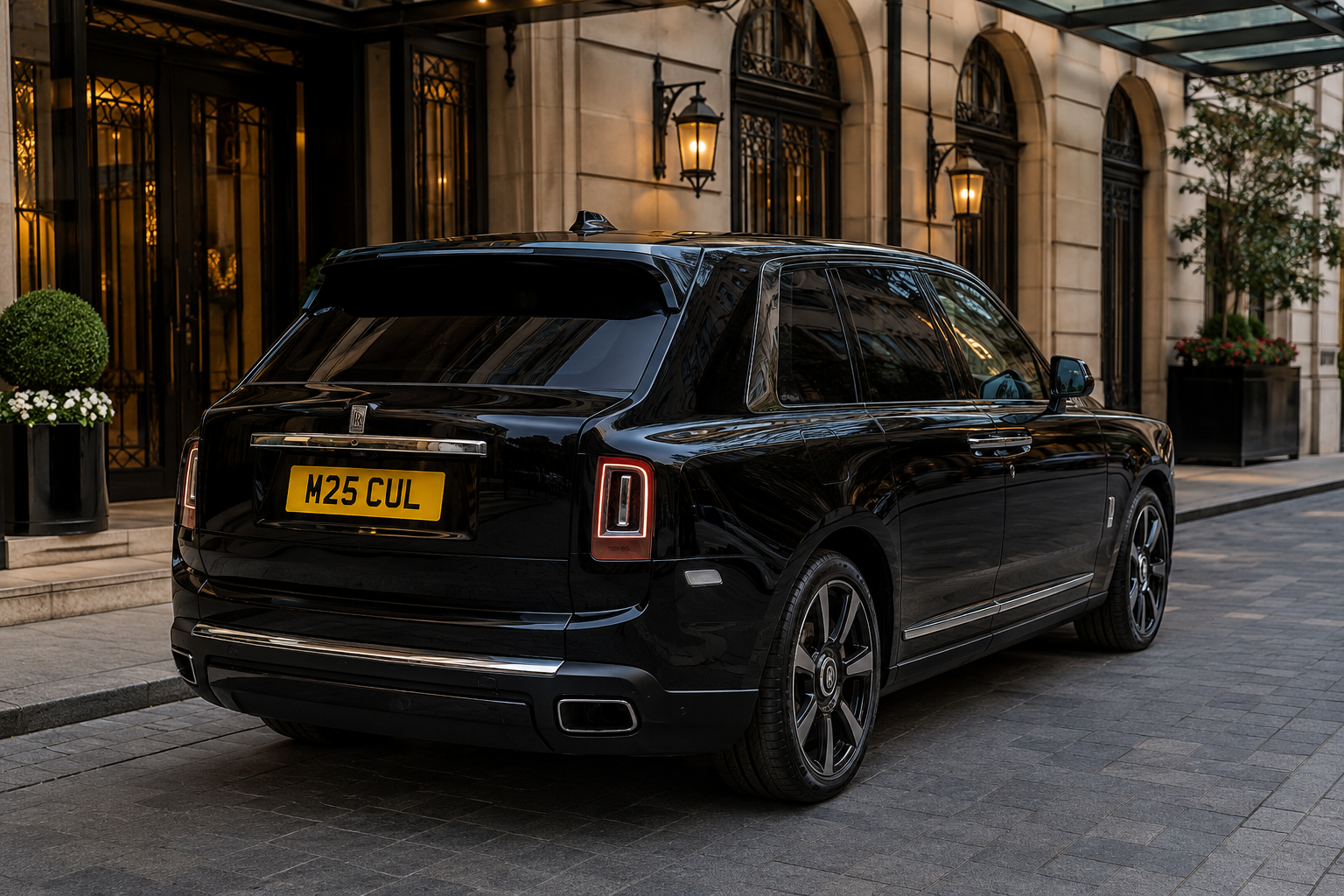 in Thetford 1 M25 Chauffeurs Ltd Professional Chauffeur Service United Kingdom Black Rolls-Royce Cullinan SUV parked on a cobblestone street in front of a luxury hotel entrance with warm lanterns. License plate M25 CUL.